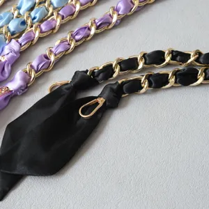 Détail d'un ruban de satin noir luxueux entrelacé avec une bandoulière en chaîne dorée