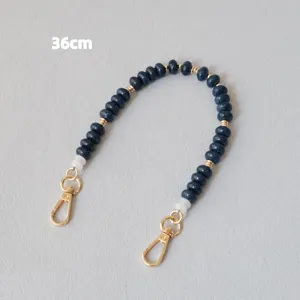 Vue détaillée d'une lanière de 36 cm en perles acryliques bleu foncé et mousquetons dorés