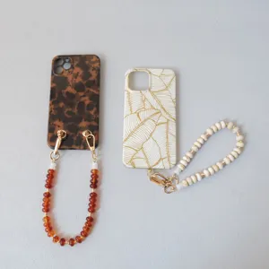 Détail de dragonnes de téléphone en perles avec coques à motifs d'écaille et de feuilles