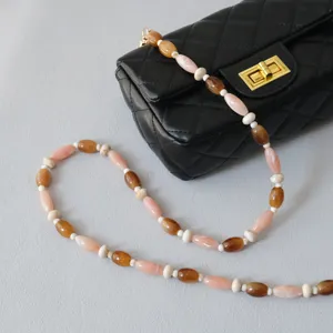 Détail de la chaîne de perles en acrylique caramel et rose sur un sac matelassé