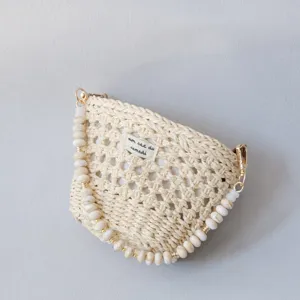 Détail d'un sac tissé crème avec une bandoulière en perles acryliques chic