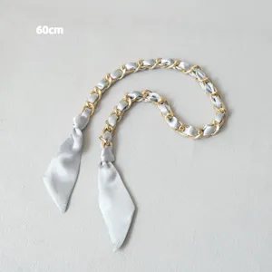 Détail de la bandoulière chaîne dorée de 60 cm entrelacée de ruban de soie bleu clair