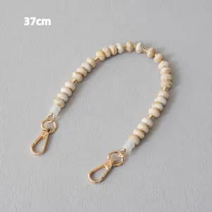 Detail view of a marbled acrylic beaded strap with golden metal clasps, 37cm in length