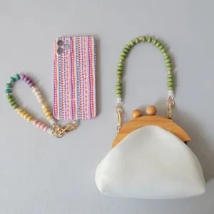 Detailed view of colorful acrylic beaded phone chain and white handbag with green handle