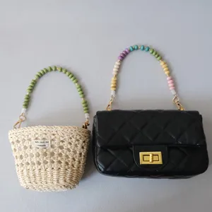 Detailed view of colorful acrylic beaded straps attached to straw and black quilted bags