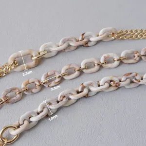 Dettaglio macro di catena in acrilico beige e metallo dorato con misure da 2,3 e 1,8 cm