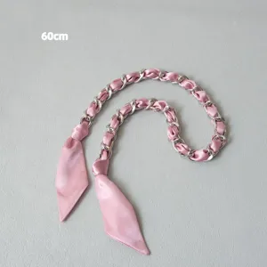 Détail d'une bandoulière de 60 cm en foulard de soie rose avec chaîne argentée.