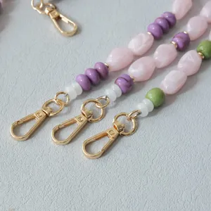 Gros plan d'une chaîne en perles d'acrylique colorées avec mousquetons dorés pour sacs