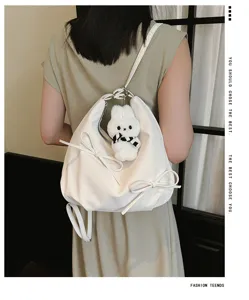 Stylish white bowknot backpack with a cute bunny plush charm shown on model back.