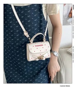 Detailed shot of white polka dot crossbody bag with fashion print and gold buckle