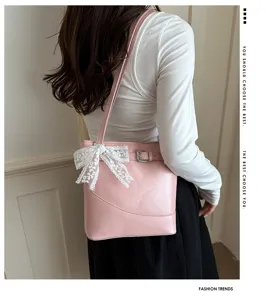 Modella con borsa a secchiello rosa con fiocco in pizzo bianco e fibbia a cintura.