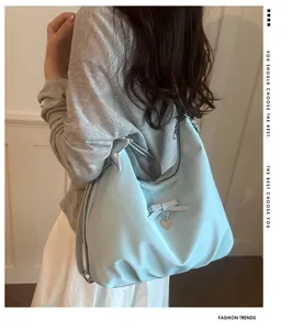 Close-up of a light blue multifunctional hobo bag with bow and heart pendant detail.