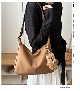 Détail de profil d'un sac à bandoulière marron en cuir grainé avec charme d'ours