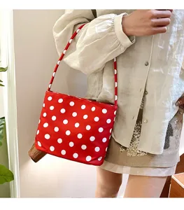 Primer plano de bolso tipo cubo rojo con lunares llevado por modelo
