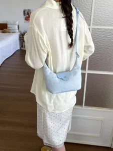 Gros plan d'un sac à bandoulière croissant bleu clair avec étoiles montrant la coupe sur modèle