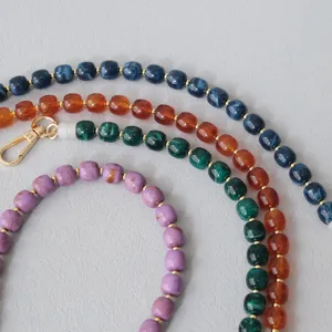 Dettaglio di catene in acrilico colorato con distanziatori dorati e chiusura a moschettone
