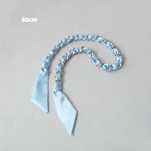 Gros plan d'une bandoulière en foulard de soie bleu clair et chaîne argentée