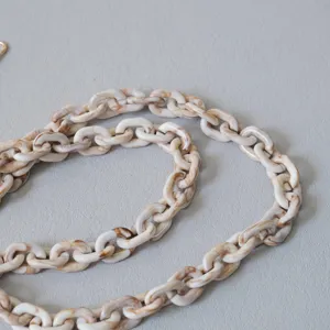 Dettaglio ravvicinato di catena in resina acrilica marmorizzata beige per borse e cellulari