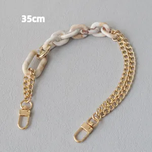 Dettaglio della tracolla a catena a maglie miste in resina beige e metallo oro
