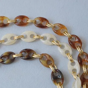 Macro detail of retro resin pig nose chain straps for bags and phones in marbled colors.
