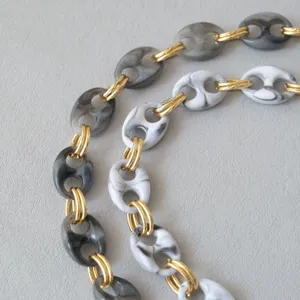Detail of chunky resin pig nose chain with marble texture and gold rings for bag strap