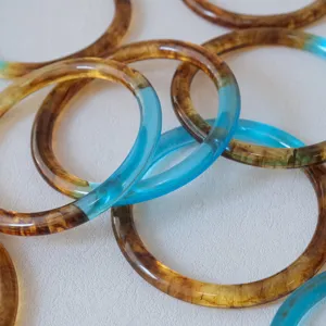 Vista detallada de anillos de resina vintage bicolores con texturas ámbar y azul cian