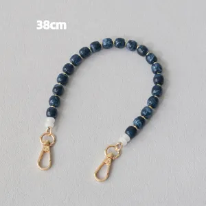 Dettaglio della tracolla da 38cm in perle acriliche blu marmorizzate con ganci dorati