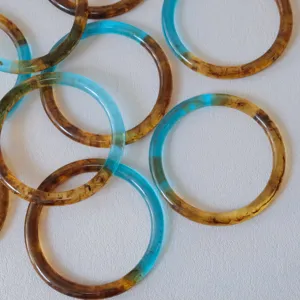 Primer plano de anillos de resina ámbar y azul para asas de bolsos hechos a mano.