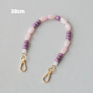 Vue détaillée d'une chaîne en perles acryliques rose et violette de 38 cm avec fermoirs dorés.