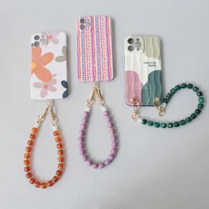 Dettaglio di cinturini per cellulare in perle acriliche colorate su cover decorate.