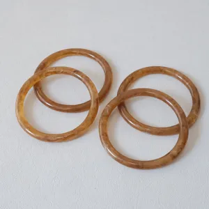 Primer plano de cuatro anillos de resina ámbar con textura jaspeada para joyas y asas de bolso