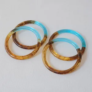 Detalle de asas de resina bicolor con texturas marmoleadas en azul y ámbar para manualidades.