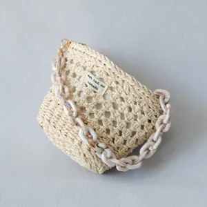 Dettaglio ravvicinato di una mini borsa beige intrecciata con catena in resina acrilica