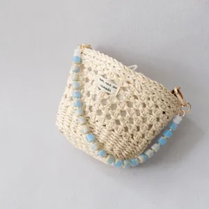 Vista dettagliata di borsa intrecciata crema con tracolla in perle acriliche blu e grigie