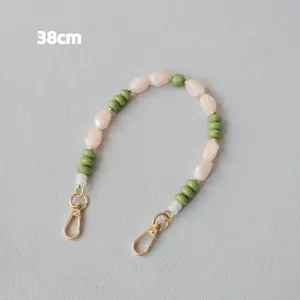 Vue détaillée d'une sangle de sac en perles acryliques de 38 cm avec pierres crème et vertes.