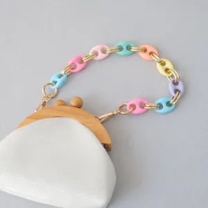 Primer plano de una cadena de resina multicolor en un bolso blanco con marco de madera