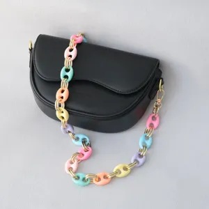 Detalle de una cadena de resina colorida en un bolso de hombro de cuero negro mate