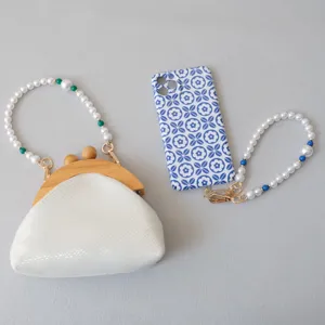Dettaglio di catene in perle bianche per pochette e custodie per telefoni
