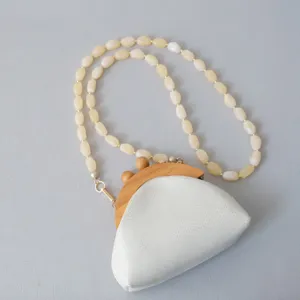 Detailweergave van de melkwitte acryl kralenketting met houten sluiting voor tasriemen