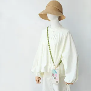 Detailweergave van groene acryl kralen crossbody telefoonketting op een witte blouse detail
