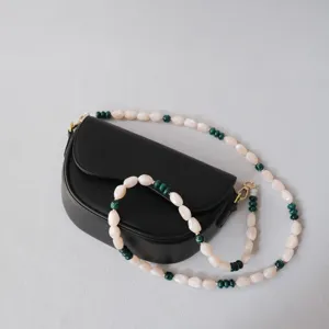 Détail de la bandoulière en perles acryliques crème et vertes sur un sac noir