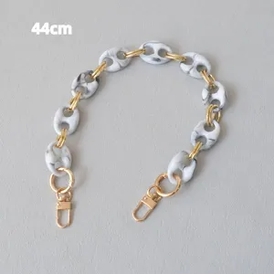 Detail view of marble-patterned resin bag chain with gold-toned swivel clasps