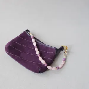 Vue détaillée d'une bandoulière en perles acryliques sur un sac en daim violet