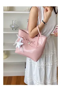 Elegant pink faux leather tote bag with bow detail and star charm shown on a model