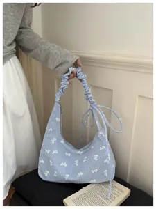 Detail view of blue gingham underarm bag with white bow prints and scrunchie handle.