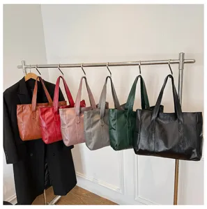 Fila di borse tote vintage in vari colori appese a un supporto per lo stile da ufficio.