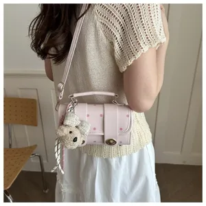 Close-up detail of a pink polka dot pillow bag with a cute teddy bear charm accessory.