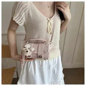 Fashionable light pink polka dot pillow bag with cute bear charm worn by a model