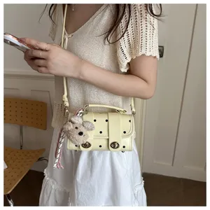 Detail view of a cute cream polka dot pillow bag worn as a crossbody by a model