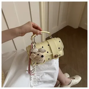 Detail view of a cute cream polka dot pillow handbag with a plush teddy bear charm
